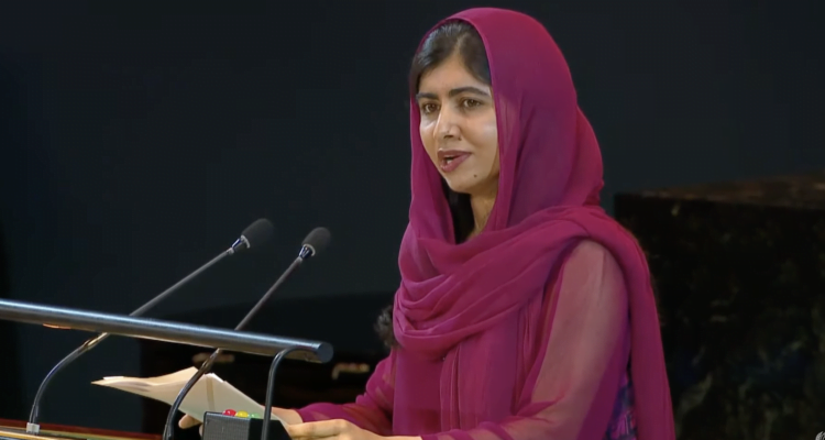 Malala Yousafzai, at the UN podium, in a dark red head scarf, stresses urgency and benefit of universal access to education.