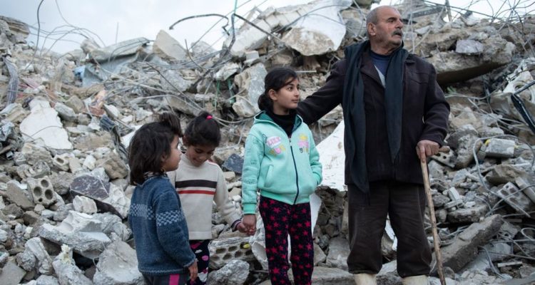 © UNICEF/Hasan Belal A family from the Rumaila area in Jableh district, in northwestern Syria stands close to their destroyed house.